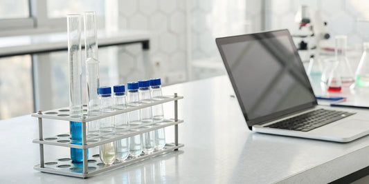 Lab grade peptides in vials on a table next to a laptop for online research.